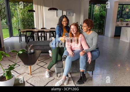 Diverses amies féminines assis sur le banc dans le salon avec smartphone montrant la jambe prothétique Banque D'Images