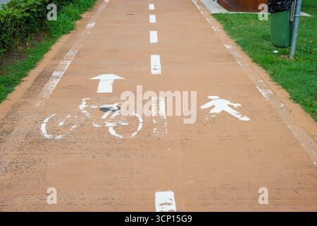 Piste piétonne et cyclable partagée avec des marques blanches. Chemin asphalté dans la ville. Marquage routier appliqué sur la route. Signalisation des voies piétonnes et cyclables Banque D'Images