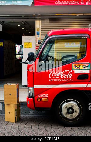 TOKYO, JAPON - 27 OCTOBRE 2024 - photo verticale d'un camion Coca Cola rouge et d'une boîte en carton sur le sol Banque D'Images