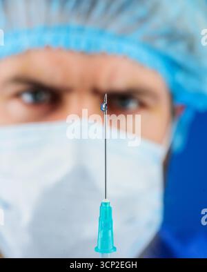 Injection. Vaccination. Docteur en masque médical tient seringue avec vaccin. Solution injectable. Goutte de médicament, médicament liquide ou médicament sur le bout Banque D'Images