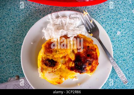 Assiette de gâteau de riz bibingka local garnie de fromage fondu et œuf salé avec noix de coco râpée sur le côté à Bulacan, Philippines Banque D'Images