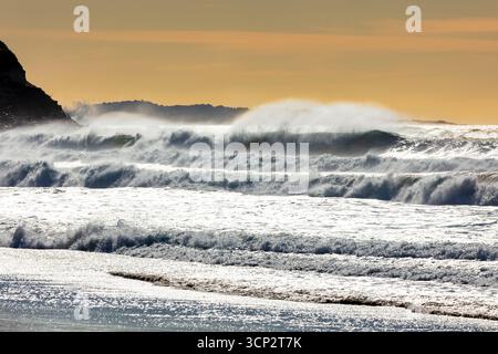 Photographie de vagues de la mer de Tasman s'écrasant sur Jones Beach contre un ciel orange près de la ville de Kiama Downs dans la région d'Illawarra en Nouvelle-Galles du Sud. Banque D'Images