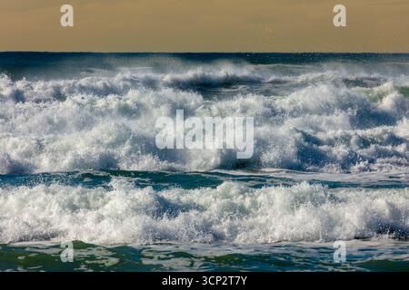 Photographie de vagues de la mer de Tasman s'écrasant sur Jones Beach contre un ciel orange près de la ville de Kiama Downs dans la région d'Illawarra en Nouvelle-Galles du Sud. Banque D'Images