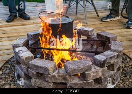 Le pot robuste se trouve sur la grille du gril au-dessus du feu actif produisant des flammes orange vives avec une mise au point sélective Banque D'Images