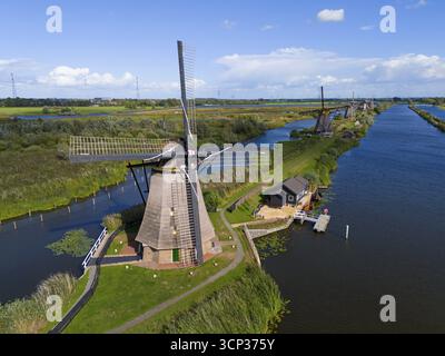 Scène de paysage tranquille avec un moulin à vent et une petite maison le long d'un canal sous un ciel bleu, vue aérienne, moulins à vent, Kinderdijk, Overwaard-Polder, UNESC Banque D'Images