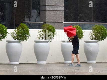 Hong Kong, Chine. 24 septembre 2025. Un homme marche contre un vent fort au Hong Kong Convention and Exhibition Center à Hong Kong, dans le sud de la Chine, 24 septembre 2025. L'Observatoire de Hong Kong a émis le signal d'ouragan n° 10, l'alerte de haut niveau, mercredi à 2h40 heure locale alors que le super typhon Ragasa tourbillonne. C’était la deuxième fois que l’alerte la plus élevée était activée cette année après le passage du typhon Wipha le 10 juillet. Hong Kong n'a pas répété le signal no 10 en un an depuis 1964. Crédit : Chen Duo/Xinhua/Alamy Live News Banque D'Images