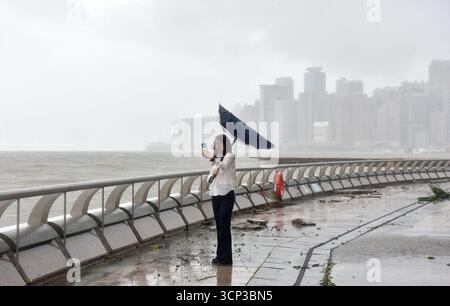 Hong Kong, Chine. 24 septembre 2025. Une femme prend des photos au milieu du vent fort et des précipitations au port Victoria à Hong Kong, dans le sud de la Chine, le 24 septembre 2025. L'Observatoire de Hong Kong a émis le signal d'ouragan n° 10, l'alerte de haut niveau, mercredi à 2h40 heure locale alors que le super typhon Ragasa tourbillonne. C’était la deuxième fois que l’alerte la plus élevée était activée cette année après le passage du typhon Wipha le 10 juillet. Hong Kong n'a pas répété le signal no 10 en un an depuis 1964. Crédit : Chen Duo/Xinhua/Alamy Live News Banque D'Images