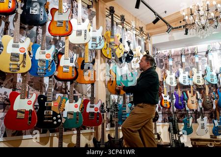Crispin Weir, copropriétaire de Regent Sounds, tient une guitare exposée dans le célèbre magasin de guitare et studio de musique Denmark Street qui relance après une rénovation majeure dans le centre de Londres. Date de la photo : mercredi 24 septembre 2025. Banque D'Images