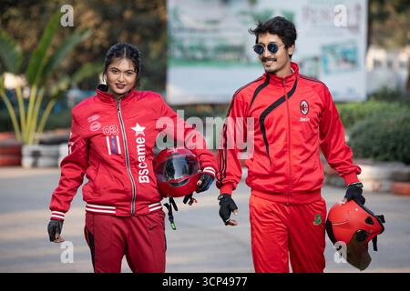 Homme élégant et femme en survêtements rouges avec casques à une piste de course Banque D'Images