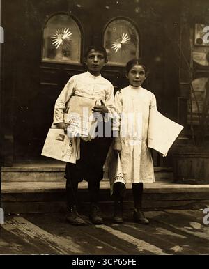 Newsgirl & Boy Selling Around Saloon Entrances, Bowery, New York, 1910 - Lewis Hine (1874-1940) sociologue américain et photographe muckraker Banque D'Images