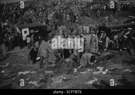 Quand la mort de l'air a frappé la colline de Farnborough -- la sombre scène sur la colline où les spectateurs ont été tués et les blessés sont couchés sur le sol pendant que les premiers soins sont donnés. En arrière-plan est une ambulance et une foule qui semble déconcertée et stupéfaite.vingt personnes - le pilote John Derry et un passager et 18 spectateurs ont été tués et 35 spectateurs ont été blessés lorsque le prototype No.1 du chasseur à réaction semi-secret de Haviliand 110 tous temps a explosé au spectacle aérien de Farnborough (Hampshire) ce jour-là (samedi). Les spectateurs étaient sur une colline frappée par un moteur en feu du plan Banque D'Images
