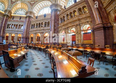 Bibliothèque du Congrès salle de lecture principale Fisheye Washington DC // WASHINGTON DC — la salle de lecture principale de la Bibliothèque du Congrès offre une vue fisheye de son intérieur grandiose, avec des rangées de bureaux en bois équipés de lampes traditionnelles. L'architecture comprend des colonnes de marbre ornées, des fenêtres cintrées avec des vitraux et des balcons donnant sur le vaste espace. Des étagères remplies de nombreux volumes bordent les murs, accessibles depuis les niveaux supérieurs. Le plafond complexe et la moquette à motifs contribuent à son atmosphère majestueuse. La Bibliothèque du Congrès, créée en 1800, est Banque D'Images