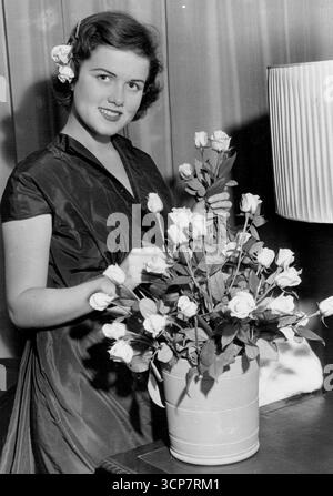 Dans Sun-suit, elle a rencontré Farouk.Mimi et Mother Come to Town - avec l'agent de publicité.Mimi Medart, fille américaine de 16 ans 'dont la main-Roi-Farouk-embrassé', fait une jolie image, comme avec des fleurs dans ses cheveux, elle arrange un vase dans son costume à l'Hôtel Savoy de Londres.Mimi est la fille d'un fabricant d'acier du Missouri. Elle rencontre Farouk en vacances avec ses parents en France, et s'envole pour Londres depuis Paris avec sa mère (anciennement actrice muette Donal Blossom) et l'agent de publicité Guido Orlando. 16 septembre 1950. Banque D'Images