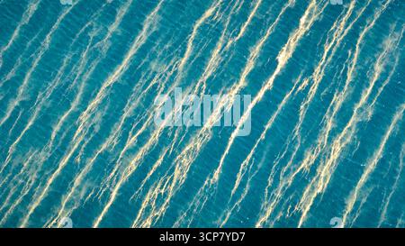Ondulations aériennes ensoleillées et texture de l'eau Top down Banque D'Images
