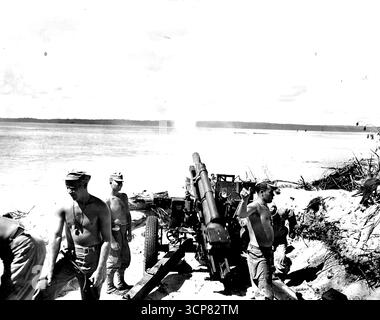 Un équipage de canons de 105 mm, creusé sur un front de mer dans les Admiralties, obture des positions de Jap sur une île adjacente. Le Pvt Osmer Messmer, à gauche, de Jasper, Indiana, attend le prochain tour alors que le caporal, Ray Dufreano de la Nouvelle-Orléans, La., au premier plan à droite, donne le signal de tirer. 05 avril 1944. (Photo de USA signal corps). Banque D'Images