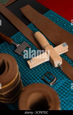 Outils de maroquinerie et préparation pour la fabrication de courroies. Configuration de travail du cuir avec outils, boucle et bandes de cuir disposées soigneusement sur un tapis, prêt pour b Banque D'Images