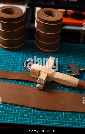 Outils de maroquinerie et préparation pour la fabrication de courroies. Configuration de travail du cuir avec outils, boucle et bandes de cuir disposées soigneusement sur un tapis, prêt pour b Banque D'Images