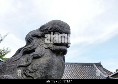 Chien lion komainu en pierre gardant l'entrée du temple Senso-ji et du sanctuaire shinto à Asakusa, Tokyo, Japon ; destiné à éloigner les mauvais esprits. Banque D'Images
