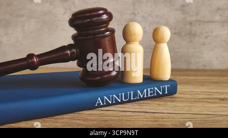 Marteau et deux figures en bois sur un livre intitulé 'ANNULATION', symbolisant la fin légale d'un mariage. Banque D'Images