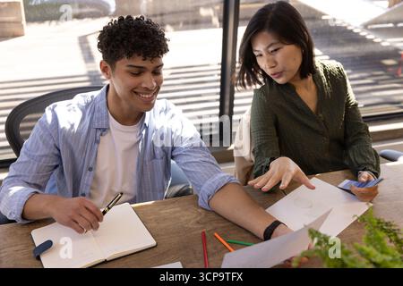Collègues collaborant à la table de conférence avec cahier, stylo et crayons de couleur dans le bureau Banque D'Images
