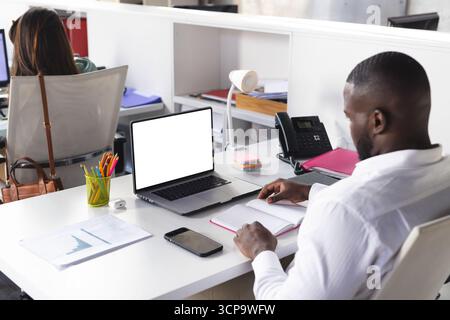 Divers collègues travaillant à des postes de travail adjacents dans le bureau avec ordinateur portable et ordinateur portable, espace de copie Banque D'Images