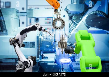 Robot industriel de soudage et robot de préhension travaillant avec des pièces métalliques sur usine intelligente, sur fond de couleur bleu machine, industrie 4,0 Banque D'Images