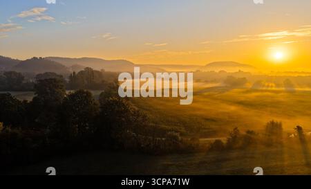 Lever de soleil doré sur paysage de campagne brumeuse Banque D'Images