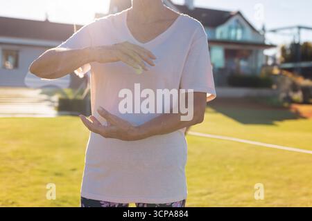 Femme âgée debout sur une pelouse bien entretenue devant les maisons modernes portant des leggings à motifs Banque D'Images