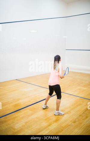 La raquette de squash est appuyée contre le plancher en bois poli dans le court de squash, montrant des lignes de démarcation bleues Banque D'Images