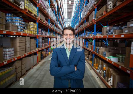 Étagères s'étendant en hauteur et tenant des rangées de boîtes en carton empilées dans l'allée lumineuse de l'entrepôt Banque D'Images