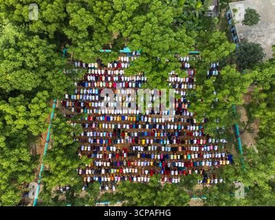 Joypurhat, Bangladesh - 22 avril 2023 : vue aérienne de personnes rassemblées à Akkelpur, Joypurhat, Bangladesh, priant, leurs vêtements colorés contrastant avec les arbres verts luxuriants. Banque D'Images