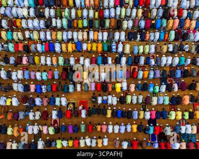 Joypurhat, Bangladesh - 22 avril 2023 : vue aérienne de rangées de personnes en prière, une tapisserie de couleurs vives contre le sol tonique de la terre, créant une scène de dévotion. Banque D'Images