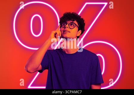 Homme en néon sur fond rouge avec signe de pourcentage lumineux Banque D'Images