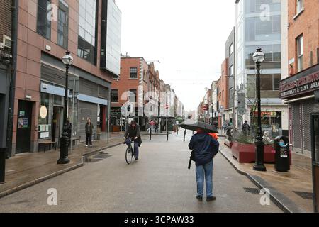 Dublin, Irlande - 19 septembre 2025 - Capel Street comme un homme avec des parapluies sur la route dans la ville de Dublin par un après-midi couvert humide dans la capitale irlandaise Banque D'Images