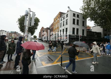 Dublin, Irlande - 19 septembre 2025 - des personnes avec des parapluies traversent Liffey Street aux feux de circulation pendant la pluie dans la ville de Dublin par un après-midi couvert humide dans la capitale irlandaise Banque D'Images