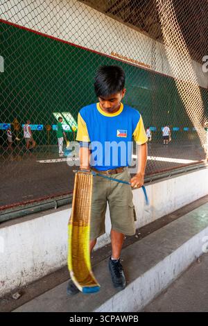 Un jeune pelotari philippin montrant comment enfiler sa cesta à un fronton Jai Alai à Cebu City, Philippines Banque D'Images