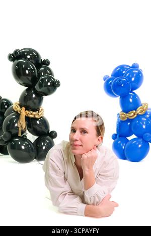 Une femme est allongée sur le sol devant deux chiens gonflables. Les chiens sont bleus et noirs Banque D'Images
