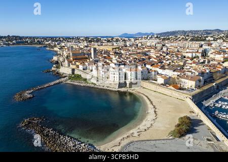 Vue aérienne de l'historique Château Grimaldi surplombant les eaux calmes et turquoises, avec des plages de sable contrastant avec les vieux murs de pierre, Antibes, Provence-Alpes-Côte d'Azur, France. Banque D'Images