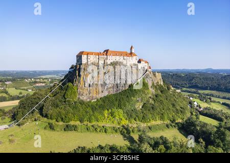 Vue aérienne du majestueux château de Riegersburg perché au sommet d'une roche volcanique, ses toits rouges contrastant avec le ciel bleu, Riegersburg, Styrie, Autriche. Banque D'Images