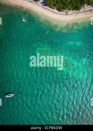 Vue aérienne d'un naufrage dans des eaux turquoises cristallines qui rodent doucement contre la rive sablonneuse, révélant des structures submergées sous la surface, Key West, Floride. Banque D'Images