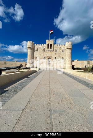 Alexandrie, Égypte - 13 février 2025 : vue de face de la citadelle médiévale de la forteresse de Qaitbay avec drapeau égyptien et canons exposés, située sur la Méditerranée Banque D'Images