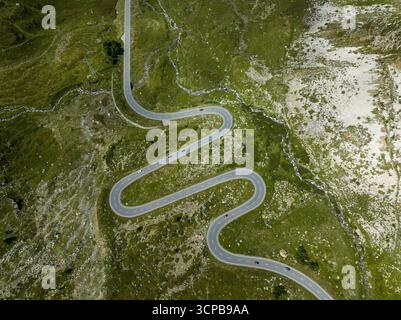 Vue aérienne de la route sinueuse coupant à travers le paysage verdoyant du col du Julier, avec des voitures naviguant dans ses courbes, col du Julier, Grisons, Suisse. Banque D'Images