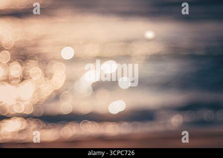 Arrière-plan flou doux de Sunset Beach Glow avec des reflets de lumière Bokeh sur l'eau calme Banque D'Images