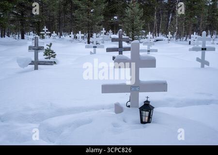 Une vue grand angle capture un cimetière recouvert de neige. De nombreuses croix en bois blanc se tiennent en évidence, leur conception simple caractéristique de Skolt Banque D'Images