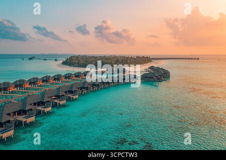 Fantastique vue aérienne des nuages de ciel du coucher de soleil de luxe Maldives. Villas aquatiques sur la baie de la lagune océanique, destination estivale exotique pour des vacances tropicales. Banque D'Images