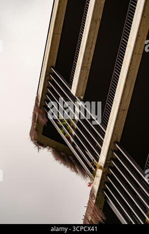 Une prise de vue architecturale en angle bas capture l'interaction saisissante des poutres en béton, des espaces sombres en retrait et des lattes horizontales sur un bâtiment moderne. Lus Banque D'Images