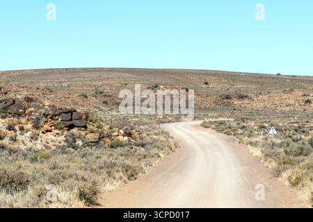 Paysage routier, avec un panneau d'avertissement de virage serré, sur la route postale historique entre Fraserburg et Sutherland dans le nord du Cap Karoo Banque D'Images