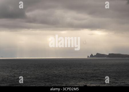 Paysage marin spectaculaire avec un vaste océan sous un ciel nuageux, avec des puits de lumière du soleil qui traversent les nuages et créent une ligne horizontale brillante Banque D'Images