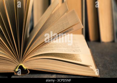 Livre ouvert reposant sur une table avec des étagères de fond remplies de plus de livres Banque D'Images