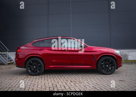Vue latérale rapprochée de la BMW X4 rouge avec fond industriel urbain Banque D'Images